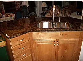 Kitchen counter finished in a dark mottled granite-look overlay with an undermount sink