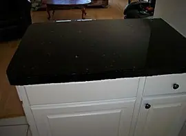 Kitchen island counter finished in black speckled granite-look overlay