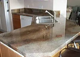 Corner kitchen counter in a mottled stone-look overlay with a sink