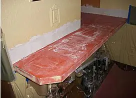Bar top with a red-orange base coat applied and drywall prep visible